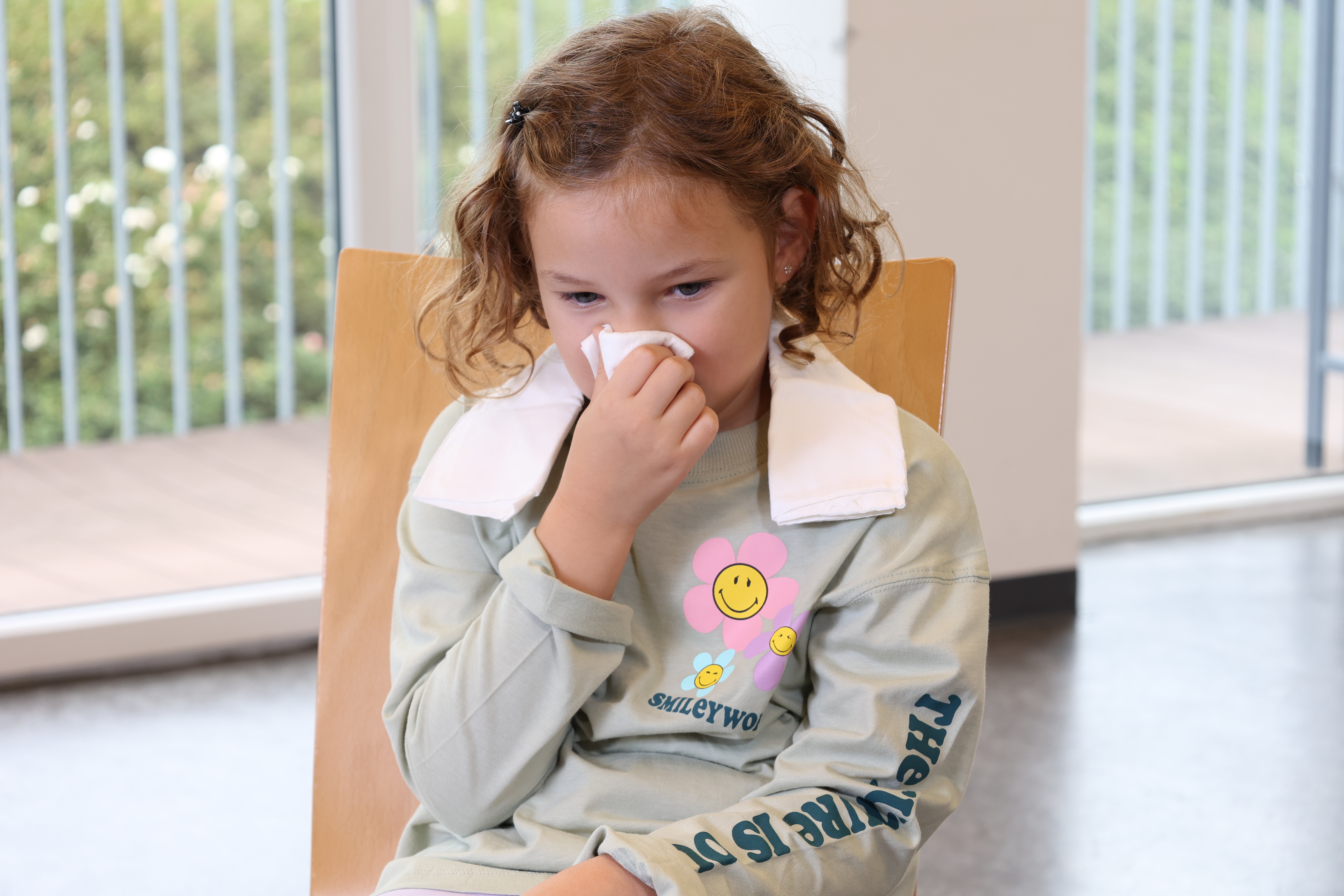 Ein Mädchen mit Nasenbluten hält sich ein Taschentuch unter die Nase.