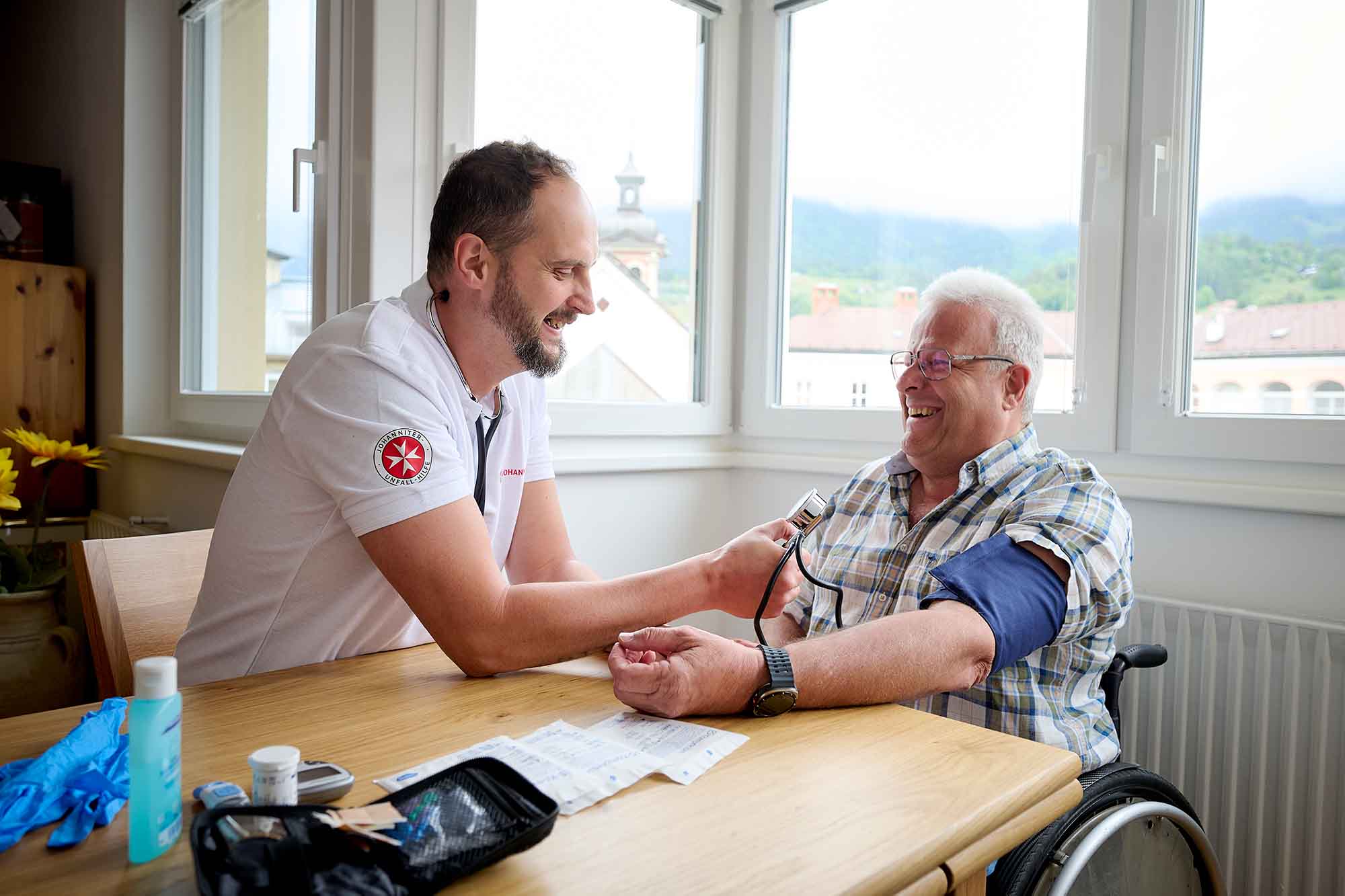 Ein Johanniter-Pfleger misst bei einem Hausbesuch bei einem Klienten den Blutdruck.