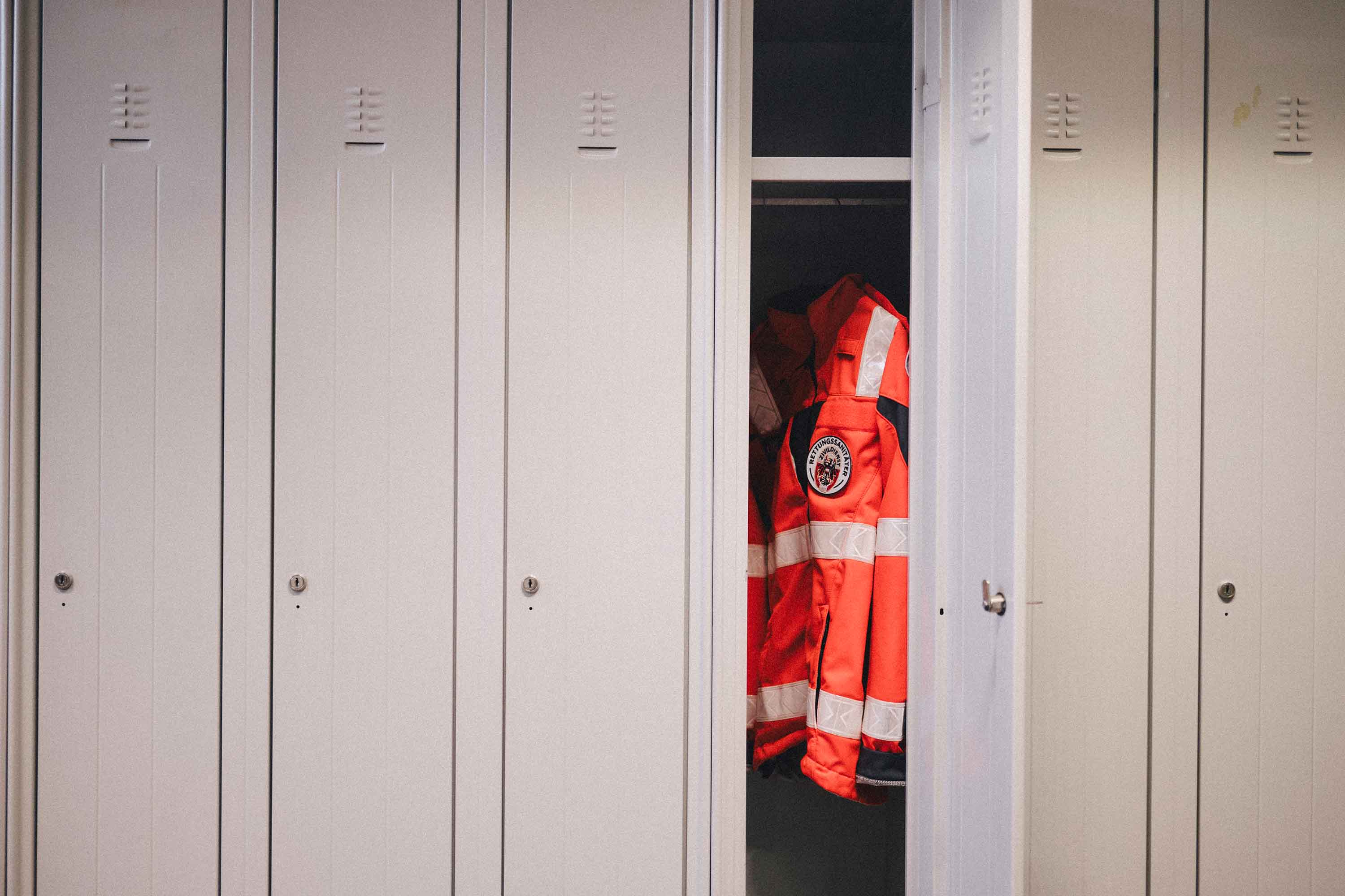 Eine Johanniter-Uniformjacke hängt in einem Spind.