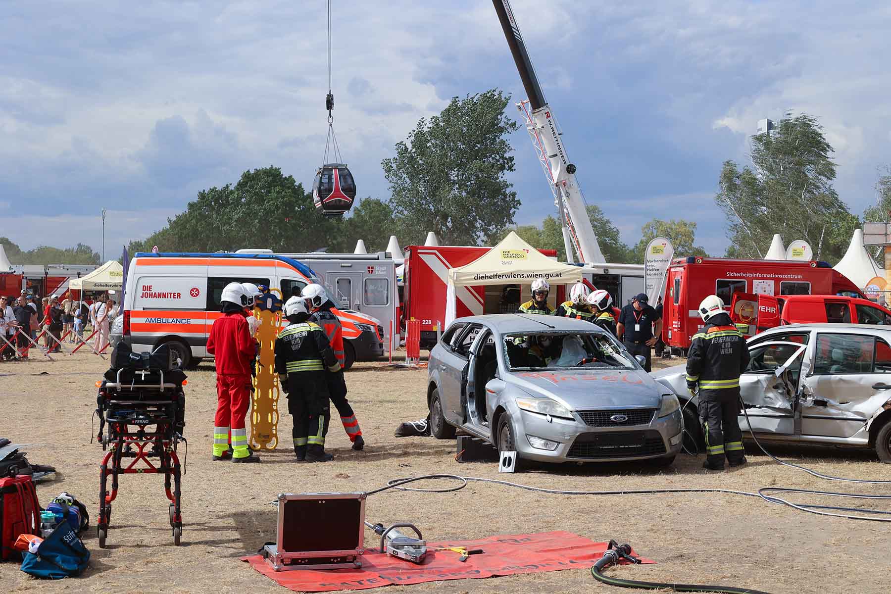 Einsatzvorführung Verkehrsunfall: Zwei zusammengefahrene Autos werden von der Feuerwehr geöffnet, Sanitäter warten auf die mögliche Versorgung der Patienten.