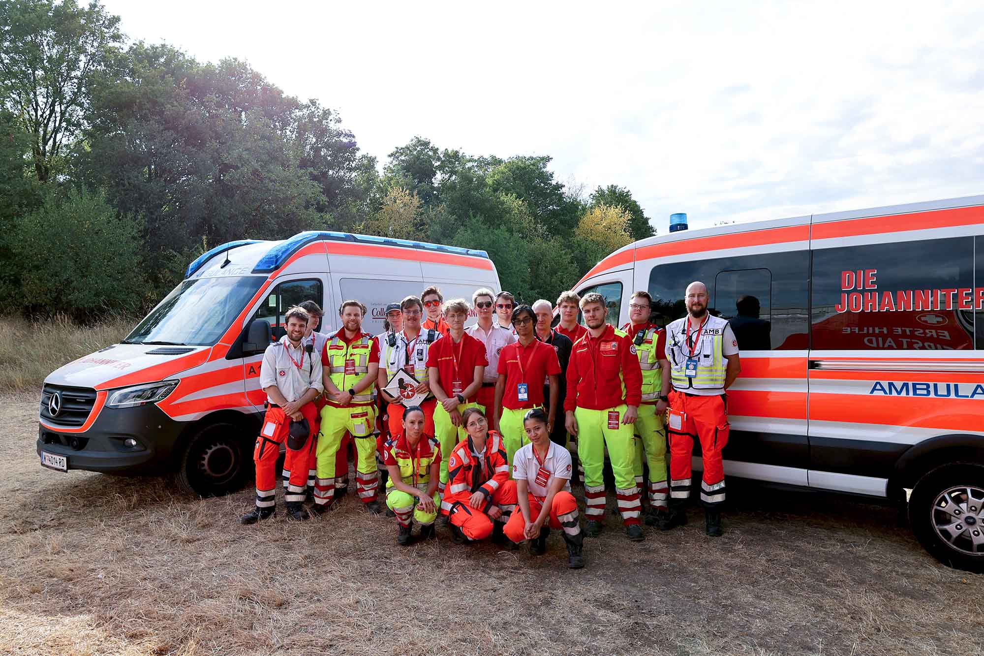 Das Team aus Sanitäter:innen von Johannitern und Samaritern vor zwei Johanniter Rettungsautos.