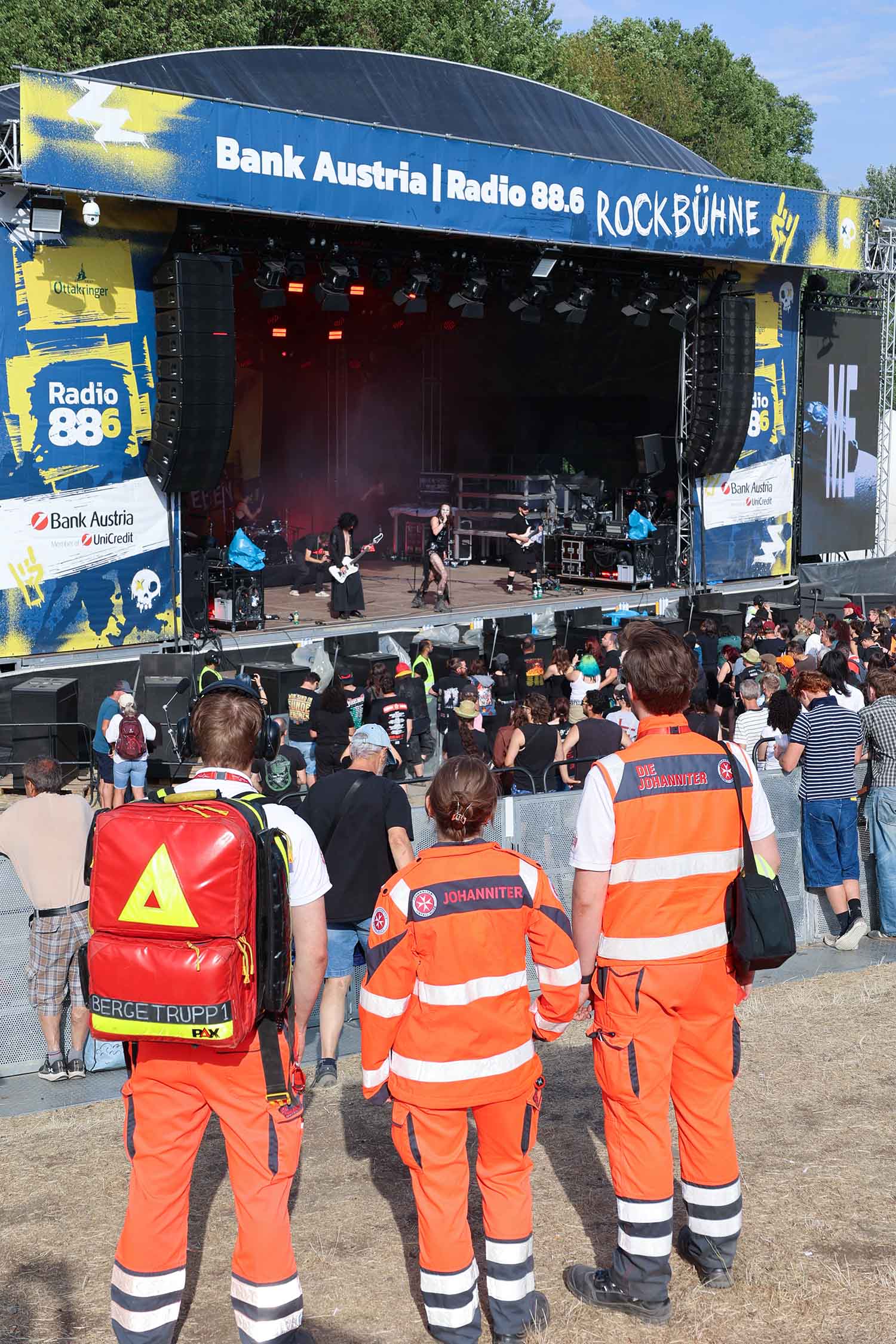 Drei Johanniter schauen beim Donauinselfest auf die Rock-Bühne, wo sie den Ambulanzdienst betreuen.