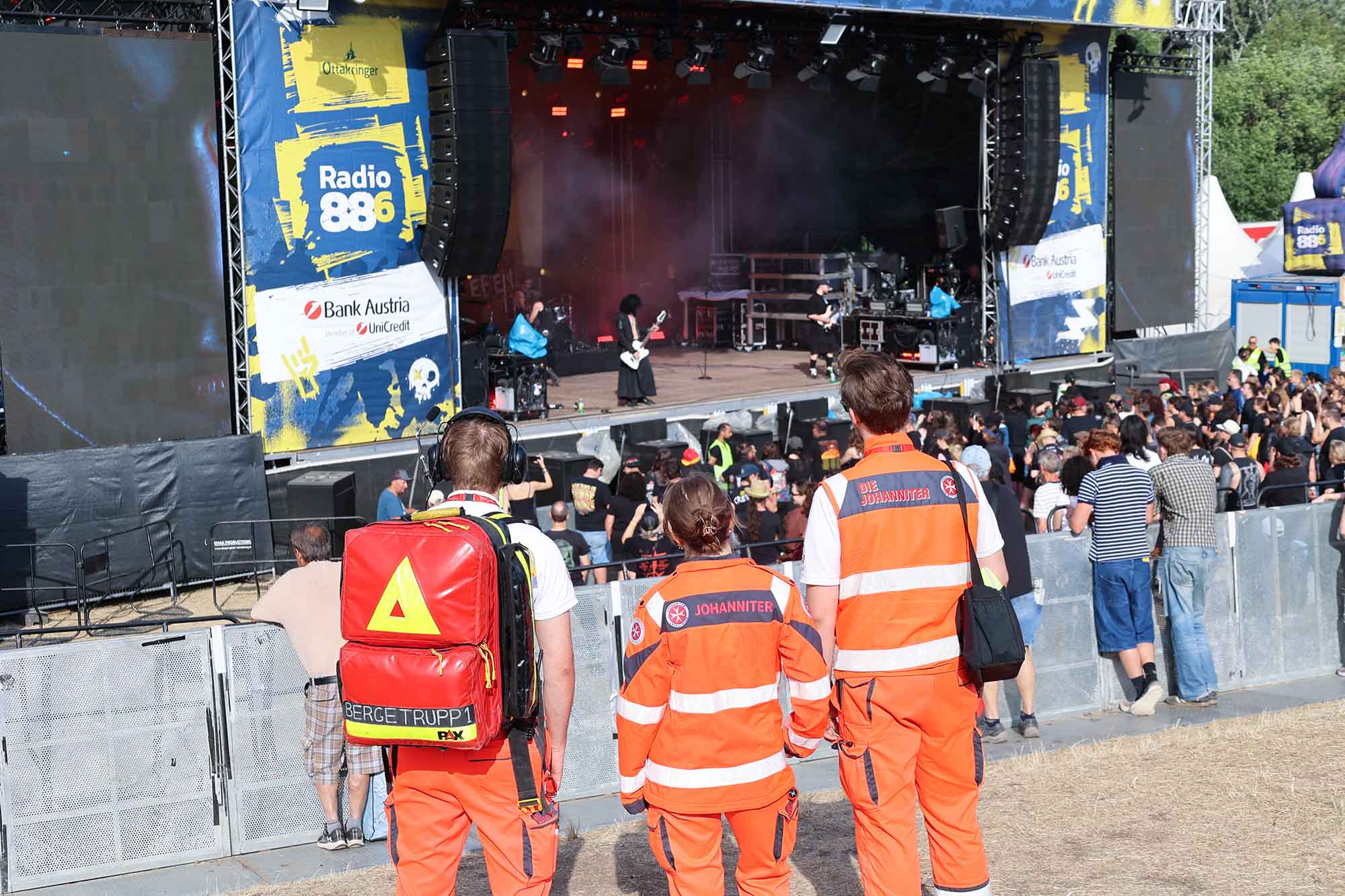 Drei Johanniter schauen beim Donauinselfest auf die Rock-Bühne, wo sie den Ambulanzdienst betreuen.