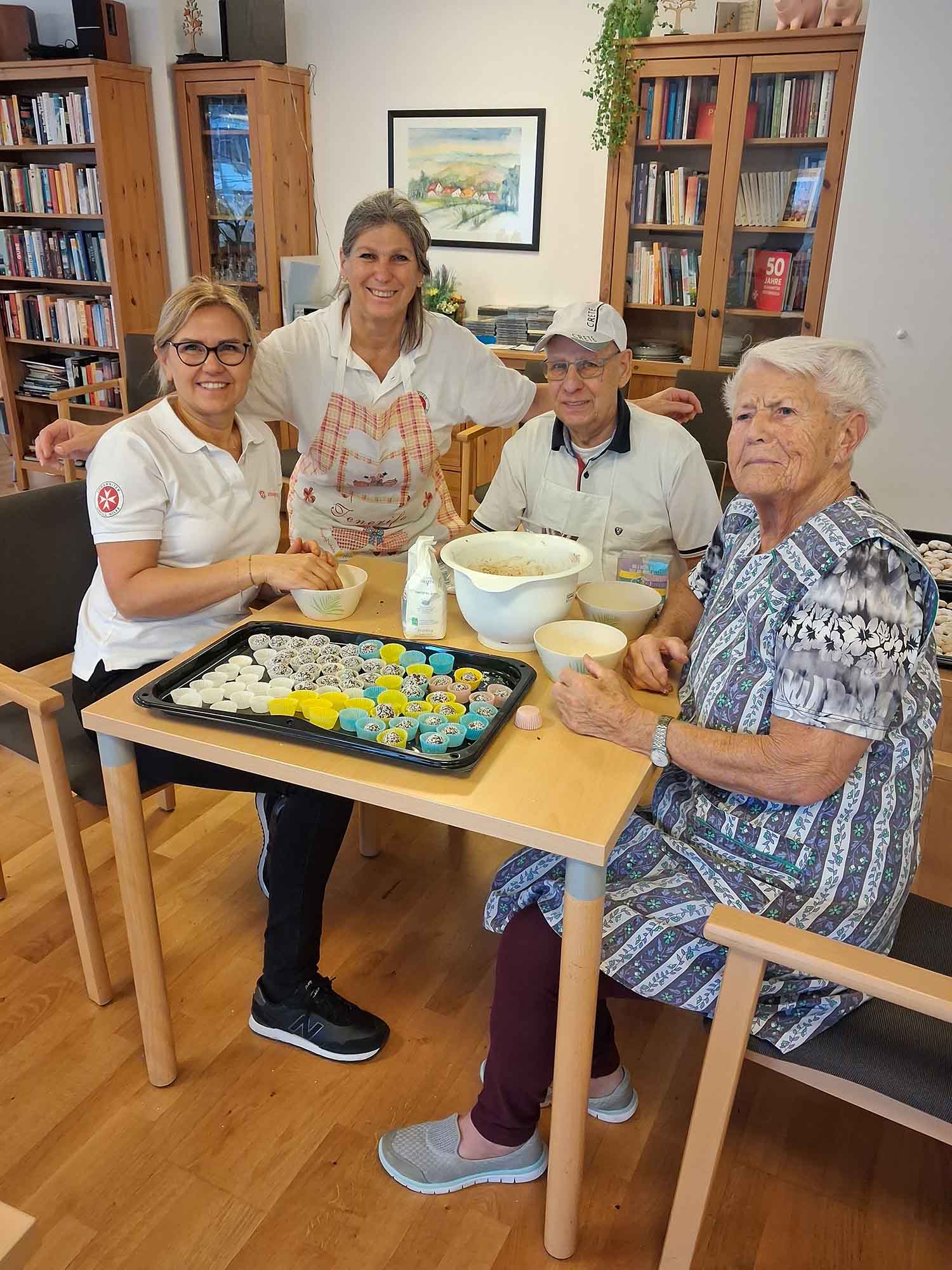 4 Personen sitzen am Tisch beim Kekse backen.